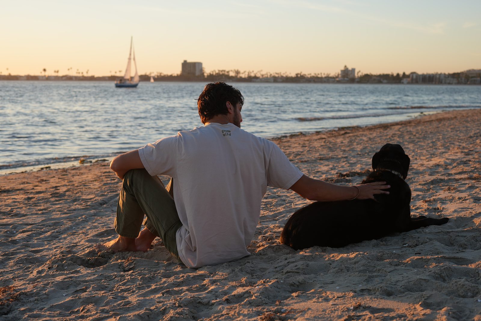 Will Jordan sitting on Mission Bay beach with his dog at golden hour